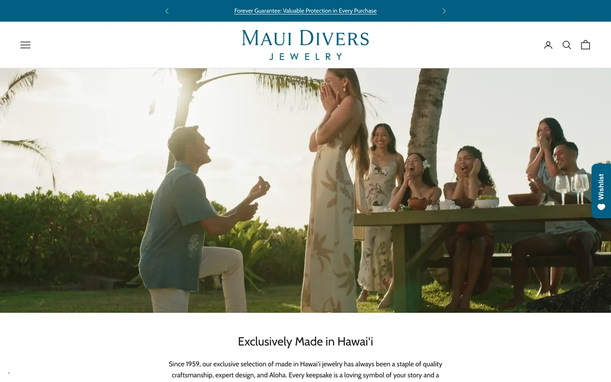 The Maui Divers Jewelry homepage on desktop, showing a blue top bar reading Forever Guarantee, a white header with a hamburger icon at the left, a centred wordmark, account, search and cart icons at the right, and a full-width hero photograph of a proposal at a beachside table.